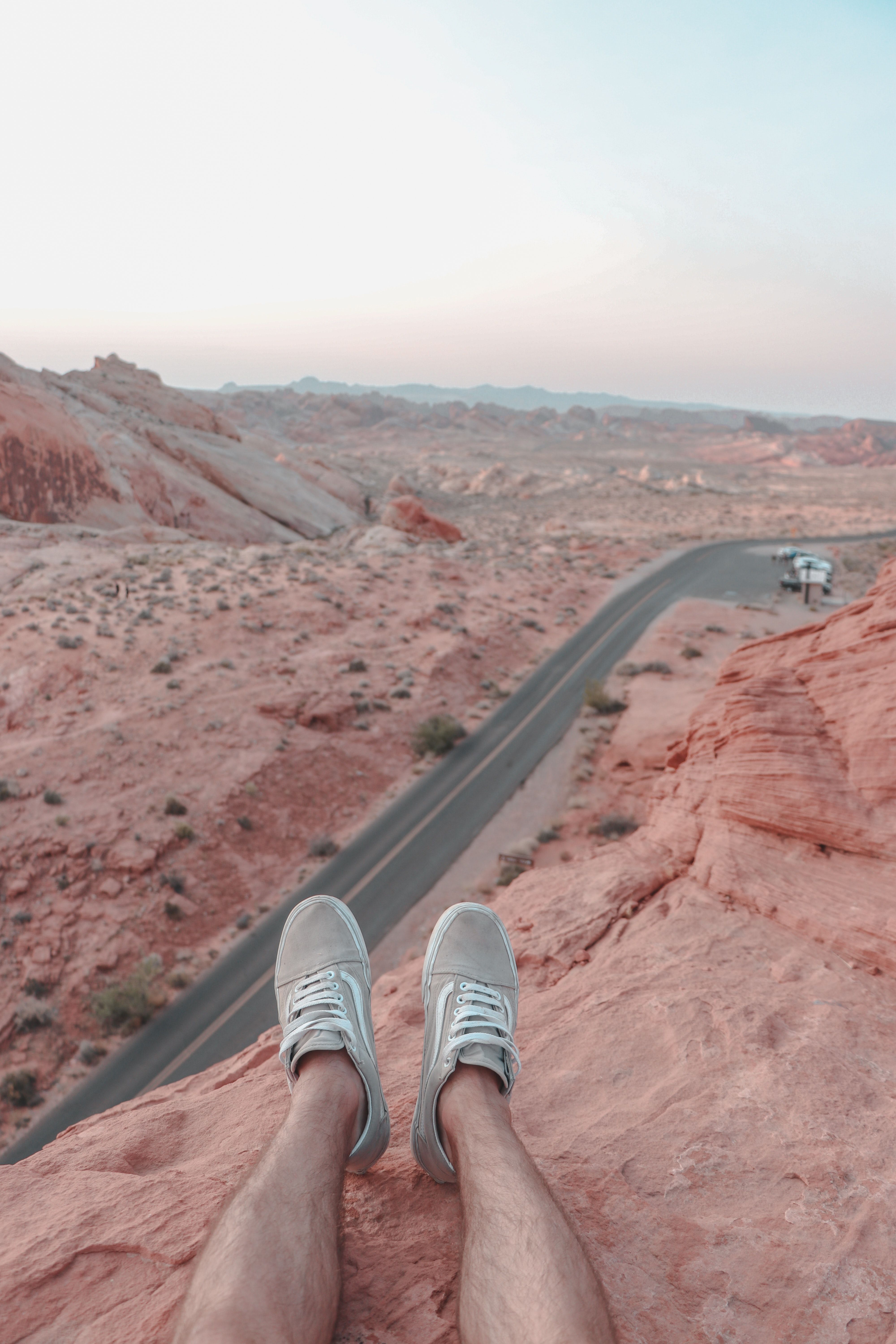Pés de uma pessoa sentada na saliência acima da estrada